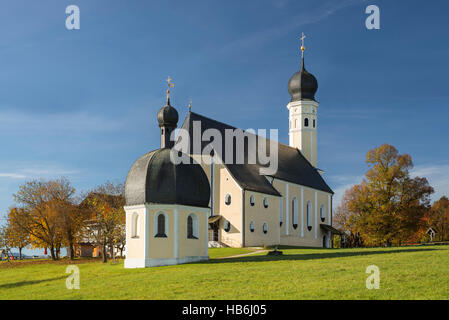 Bunte Fassade, Kirchtürme und Dach der barocken Wallfahrtskirche Wilparting und Kapelle gegen den blauen Himmel in der Morgen Sonne, Bayern, Deutschland Stockfoto