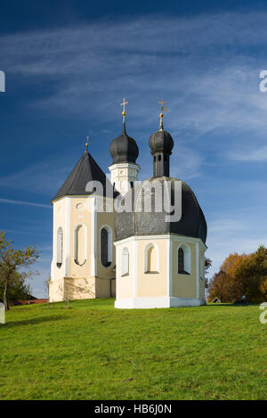 Bunte Fassade, Kirchtürme und Dach der barocken Wallfahrtskirche Wilparting und Kapelle gegen den blauen Himmel in der Morgen Sonne, Bayern, Deutschland Stockfoto