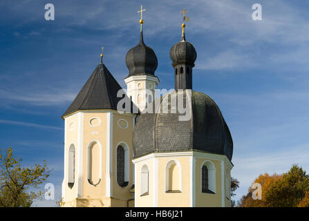 Bunte Fassade, Kirchtürme und Dach der barocken Wallfahrtskirche Wilparting und Kapelle gegen den blauen Himmel in der Morgen Sonne, Bayern, Deutschland Stockfoto