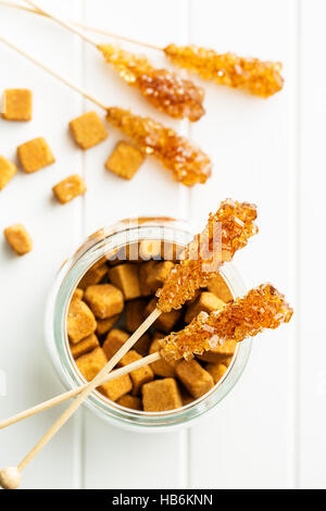 Braunen Bernstein Zucker Kristall auf hölzernen Stock und Zucker Würfel. Stockfoto