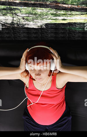 Schwangere Frau genießen Musik overhead Stockfoto