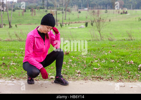 Junge Sportlerin Gefühl, Benommenheit oder mit Kopfschmerzen an einem kalten Wintertag in den Spuren von einem städtischen Park. Stockfoto