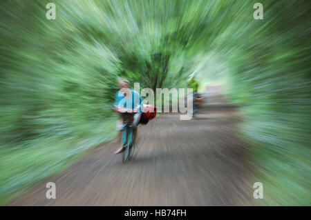 Zwei Radfahrer ein Mann und eine Frau auf einem Radweg genommen mit einer langen Belichtungszeit während zoomen, den Eindruck von Geschwindigkeit zu geben. Stockfoto