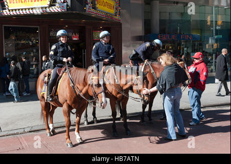 Polizei, drei weibliche Polizeibeamte des NYPD auf Pferden interagieren mit Touristen am Times Square, Manhattan, New York City Stockfoto