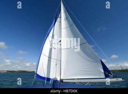 Segeln Yacht "Goosewinged" mit Genua und Großsegel auf gegenüberliegenden Seiten. Einen wunderschönen blauen Himmel in Pembrokeshire mit flauschigen Wolken. Stockfoto