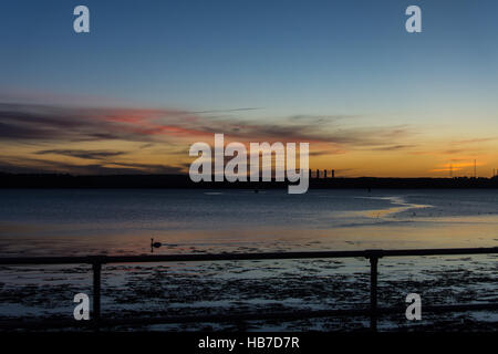 Winter-Sonnenuntergang über Pembroke mit rot und Gold, die Beleuchtung der Basis der wenigen Wolken am Himmel gesehen von Neyland Promenade. Stockfoto