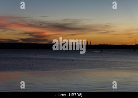 Winter-Sonnenuntergang über Pembroke Kraftwerk mit rot und Gold, die Beleuchtung der Basis der wenigen Wolken am Himmel gesehen aus Neyland pr Stockfoto