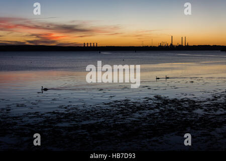 Winter-Sonnenuntergang über Pembroke mit rot und Gold, die Beleuchtung der Basis der wenigen Wolken am Himmel gesehen aus Neyland promenade. Stockfoto