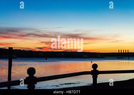 Winter-Sonnenuntergang über Pembroke Kraftwerk mit rot und Gold, die Beleuchtung der Basis der wenigen Wolken am Himmel. Von Neyland betrachtet. Stockfoto