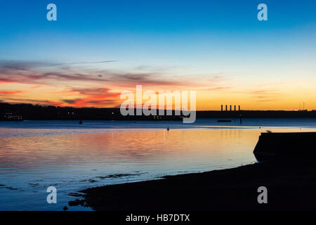 Winter-Sonnenuntergang über Pembroke Kraftwerk mit rot und Gold, die Beleuchtung der Basis der wenigen Wolken am Himmel. Von Neyland betrachtet. Stockfoto