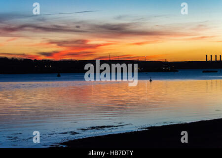 Winter-Sonnenuntergang über Pembroke Kraftwerk mit rot und Gold, die Beleuchtung der Basis der wenigen Wolken am Himmel. Aus Neyland gesehen. Stockfoto