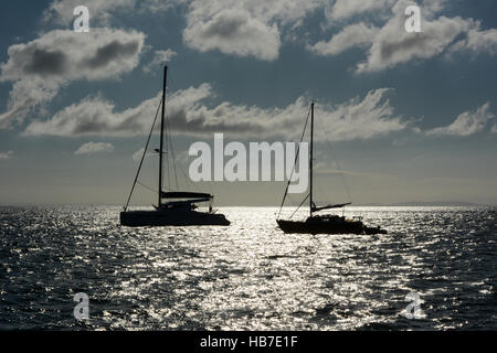 Zwei Yachten in Tenby Bucht früh an einem Sommermorgen verankert. Blauer Himmel mit weißen flauschigen Wolken und die Sonne auf dem Meer reflektiert. Stockfoto