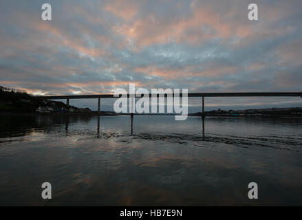 Die Cleddau Brücke am Pembroke Dock Silhouette gegen den pinken und blauen Wolken November Himmel im Wasser reflektiert Stockfoto