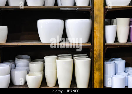 Stilvolle leere Blumentöpfe auf Holzregal indoor im Shop. Stockfoto