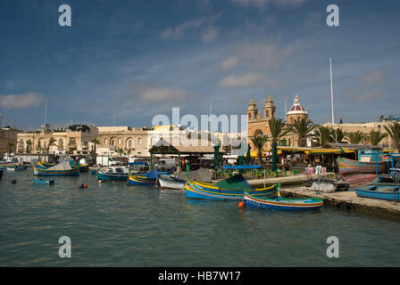 Hafenseite am kleinen Hafen von Marsaxlokk Malta mit bunten kleinen Fischerbooten und Hafengebäuden Stockfoto