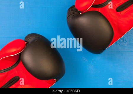 Roten und schwarzen Boxhandschuhen auf einem blauen hölzernen Schreibtisch Stockfoto