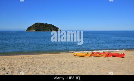 Kajaks am Strand und kleine Insel Stockfoto