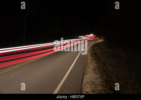 Straße in der Nacht mit Autos fahren auf und ab, wodurch Lichtspuren gekrümmt. Stockfoto