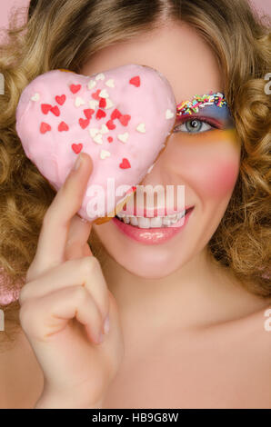 schöne Frau mit Donut im Gesicht Stockfoto