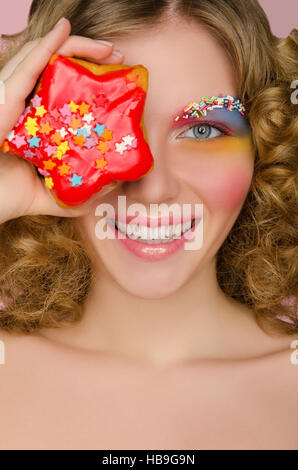 Junge Frau mit Donut im Gesicht Stockfoto