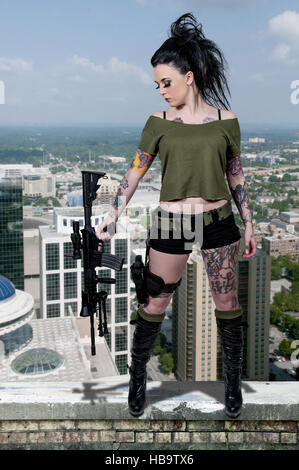 Tätowierte Frau mit Sturmgewehr und Pistole Stockfoto