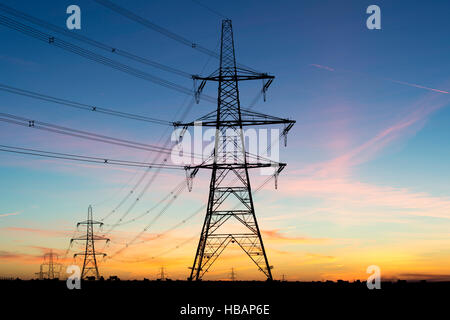 Elektrische Pylonen Silhouette vor dem Morgenhimmel. Cotswolds, England Stockfoto
