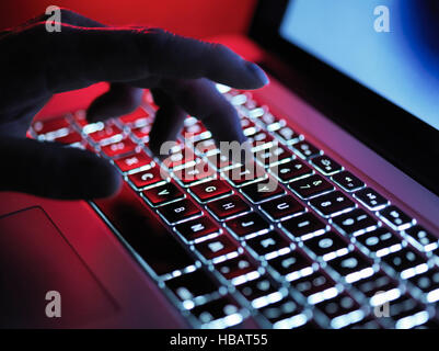 Ein dunkles Geheimnis Hand Tippen auf einen Laptop-Computer in der Nacht Stockfoto