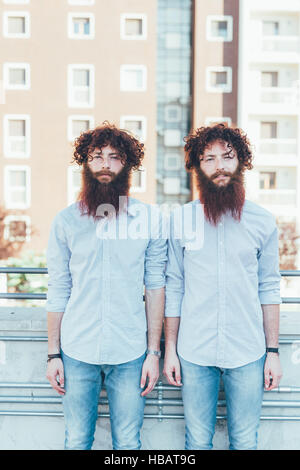 Porträt von identischen männliche Hipster Zwillinge auf Wohnung Dachterrasse stehen Stockfoto