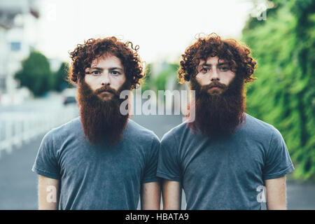 Porträt von identischen Erwachsene männliche Zwillinge mit roten Haaren und Bärten auf Bürgersteig Stockfoto