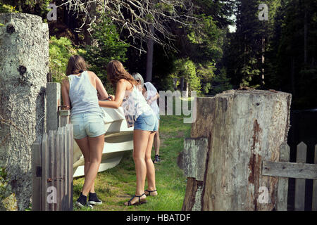 Drei Erwachsene Freundinnen bewegen Ruderboot im Garten Stockfoto
