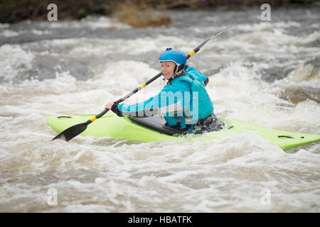 Junge weibliche Kajakfahrer paddeln Fluss Dee Stromschnellen Stockfoto