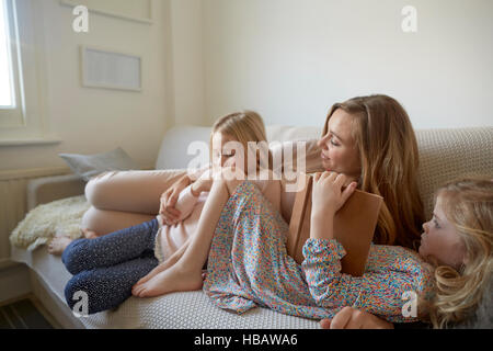 Mitte Erwachsene Frau und Töchter lesen Märchenbuch auf sofa Stockfoto