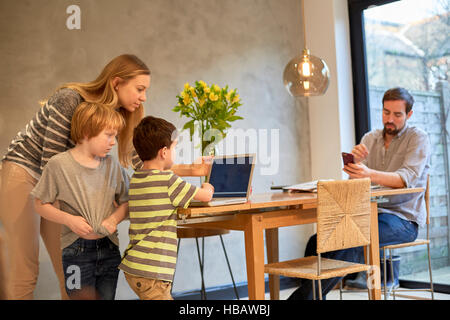 Mitte Erwachsene Frau und Söhne Blick auf Laptop auf Esstisch Stockfoto