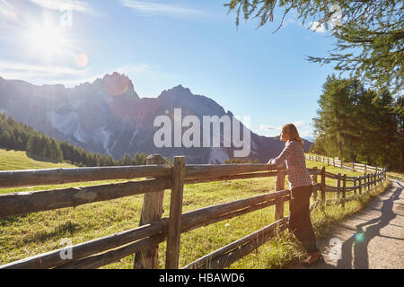 Reife Frau gelehnt Zaun mit Blick auf die Dolomiten, Sexten, Südtirol, Italien Stockfoto