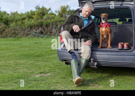 Mensch und Hund im Auto sitzen Booten entfernen Gummistiefel Stockfoto