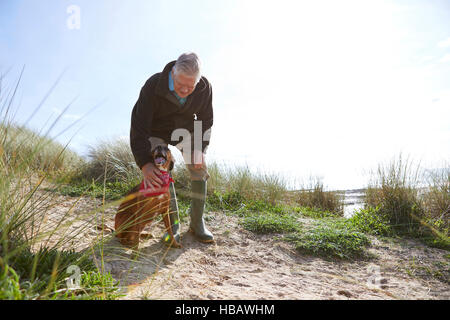 Mann streicheln Hund auf Sanddünen, Konstantin Bay, Cornwall, UK Stockfoto