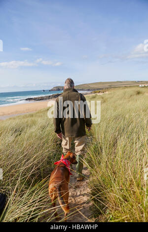 Mann zu Fuß Hund auf Sanddünen, Konstantin Bay, Cornwall, UK Stockfoto