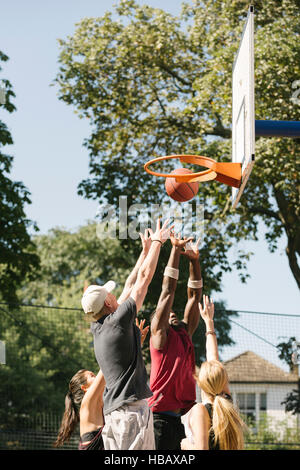 Weibliche und männliche Basketball-Spieler wirft Ball am Basketballkorb Stockfoto