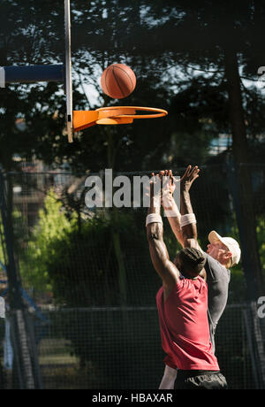 Junge männliche Basketball-Spieler wirft Ball am Basketballkorb Stockfoto