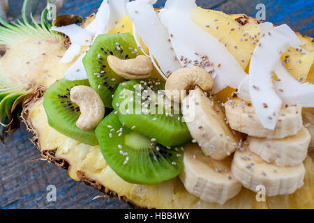 Schneiden Sie eine halbe Ananas mit Kokos, Chia, Kiwi, Cashew. Perfekt für die Dessert-Diät oder einfach eine gesunde Mahlzeit.  Liebe für eine gesunde Rohkost-Konzept. Stockfoto