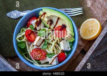 Vegane Zucchini Nudeln in eine Schüssel mit Tofu, Tomaten, Avocado und Kräutern. Perfekt für die Detox-Diät oder einfach nur eine gesunde Mahlzeit.  Liebe für eine gesunde Rohkost Stockfoto