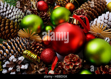 Weihnachten Hintergrund mit roten Verzierungen, grünen Kugeln und Zapfen. Weihnachts-Dekoration mit Kugeln und handgemachte Stroh Ornamente. Stockfoto