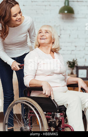 Angenehme Frau kümmert sich um ihre Großmutter im Rollstuhl Stockfoto