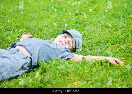 Kleinen kaukasischen jungen ruht auf dem Rasen Stockfoto