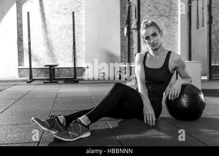 Gut aussehende sportliche Frau stützte sich auf einen med ball Stockfoto