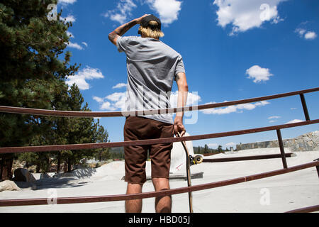 Rückansicht des jungen männlichen Skateboarder Blick auf Skate-Park, Mammoth Lakes, Kalifornien, USA Stockfoto