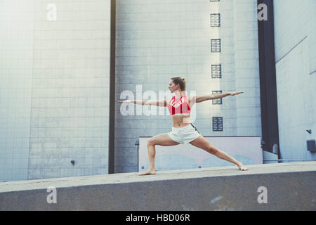 Junge Frau im Außenbereich, an Wand in Yogaposition Stockfoto