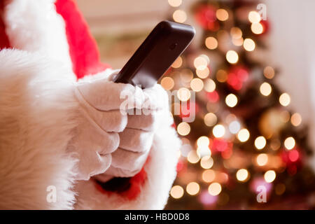 Menschenbild in Santa Kostüm hält Handy zugeschnitten Stockfoto