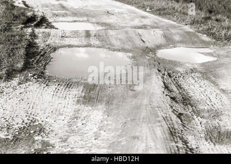 Großen Pfützen auf Feldweg am Sommertag in schwarz / weiß Stockfoto