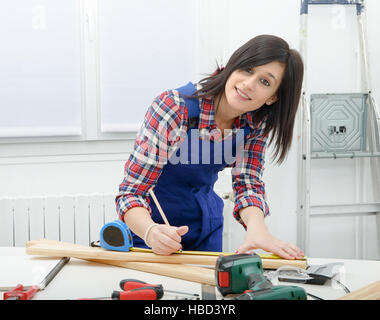 hübsche junge Frau Baumeister Messung ein Brett aus Holz Stockfoto